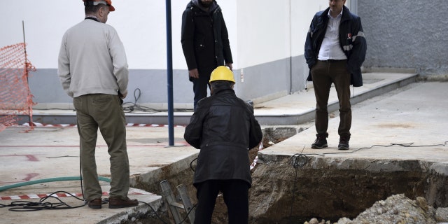 Experts check the location where an unexploded World War II bomb was found 5 meters (over 16 feet) deep, at a gas station in the northern Greek city of Thessaloniki, on Thursday, Feb. 9, 2016.