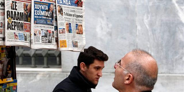 Feb. 16, 2012: A man reads the front pages of three Greek newspapers in Athens. Mounting confusion over whether Greece will get vital bailout cash to avoid defaulting next month is rekindling fears that Europe's debt crisis will spread to bigger countries like Italy.