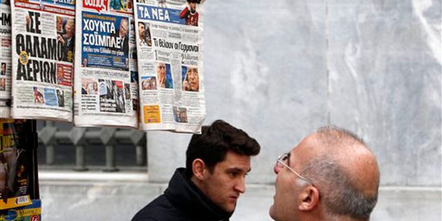 Feb. 16, 2012: A man reads the front pages of three Greek newspapers in Athens. Mounting confusion over whether Greece will get vital bailout cash to avoid defaulting next month is rekindling fears that Europe's debt crisis will spread to bigger countries like Italy.