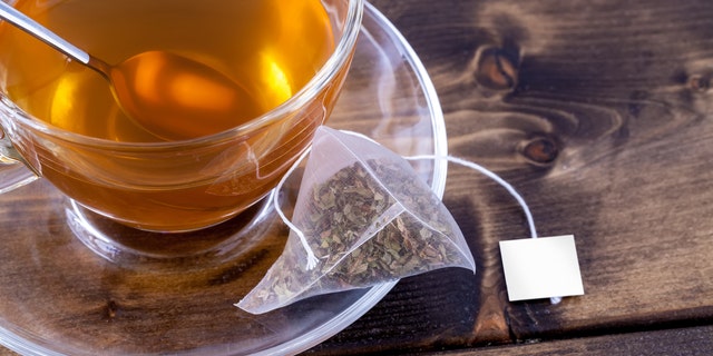 Green tea in a glass teacup on a rustic wooden table