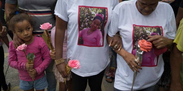 Relatives and friends hold roses during the burial service of Bruna Lace de Freitas, who was killed two days earlier by a stray bullet when she was inside her home, in Rio de Janeiro, Brazil, Friday, Oct. 28, 2016. The Brazilian Forum on Public Security says in its 10th annual report that in 2015 more people were murdered in Brazil than have been killed in war-torn Syria. (AP Photo/Leo Correa)