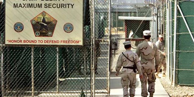 FILE - In this June 27, 2006 file photo, reviewed by a U.S. Department of Defense official, U.S. military guards walk within Camp Delta military-run prison, at the Guantanamo Bay U.S. Naval Base, Cuba. A senior U.S. official says the first of 17 detainees scheduled to be released from the Guantanamo Bay prison in January will be transferred next week, as the Obama administration continues efforts to reduce the population at the controversial detention center. (AP Photo/Brennan Linsley, File)