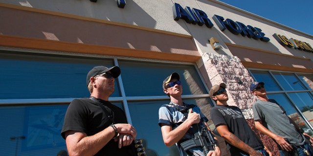 James Gardenhire, (l.), and other men stand guard outside a military recruiting center in Farmington. (Jon Austria — The Daily Times)
