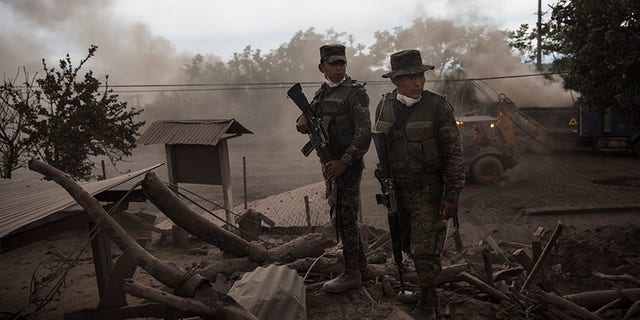 June 6, 2018: Soldiers stand guard outside a destroyed home in the disaster zone covered in volcanic ash in the El Rodeo hamlet of Escuintla, Guatemala.