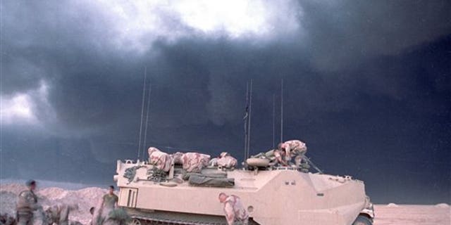 File photo from 1991 shows smoke from a burning oil well in Kuwait billowing upbehind a U.S. Marines armored vehicle.