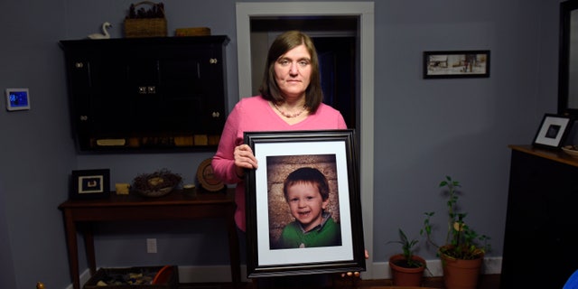 Hollie Ayers poses with a photograph of her late son, Michael, at her home in Bedford, Pa.