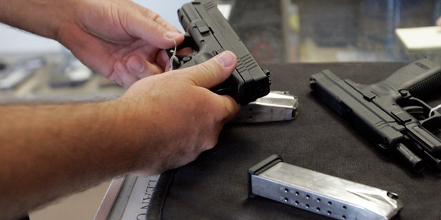 A customer inspects a 9mm handgun at Rink's Gun and Sport in the Chicago, suburb of Lockport, Illinois June 26, 2008. For the first time in U.S. history, the Supreme Court ruled on Thursday that individual Americans have the right to own guns for personal use, and struck down a strict gun control law in the U.S. capital. The landmark 5-4 ruling marked the first time in nearly 70 years the country's high court has addressed whether the Second Amendment of the U.S. Constitution protects an individual right to keep and bear arms, rather than a right tied to service in a state militia. REUTERS/Frank Polich (UNITED STATES) - RTX7DDO