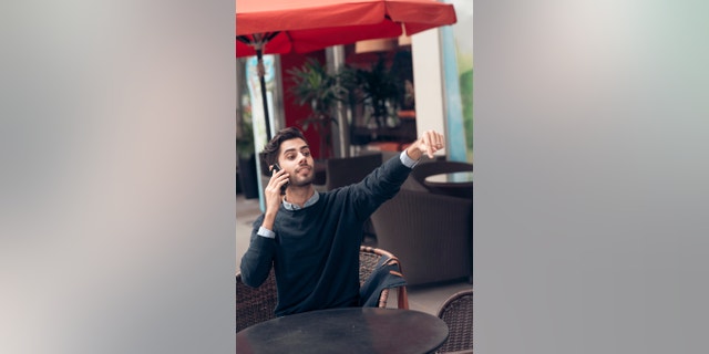 Handsome man talking on the phone and asking for waiter