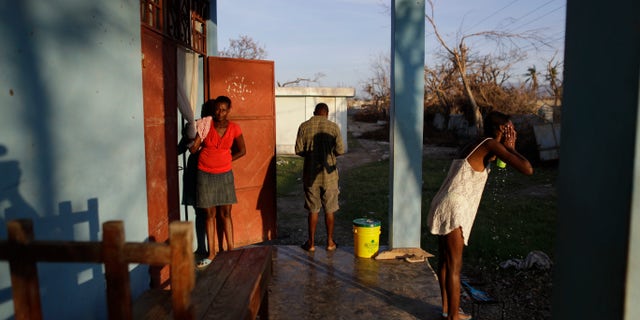 People whose homes were destroyed by Hurricane Matthew begin their day at a school where they have sought shelter in Port Salut, Haiti, Tuesday, Oct. 11, 2016. While some families like these were able to recover mattresses, furniture, and household goods from under the mud, others lost everything. The scores of people sheltering at this school have been told they have one more week before they have to move out so classes can restart. (AP Photo/Rebecca Blackwell)