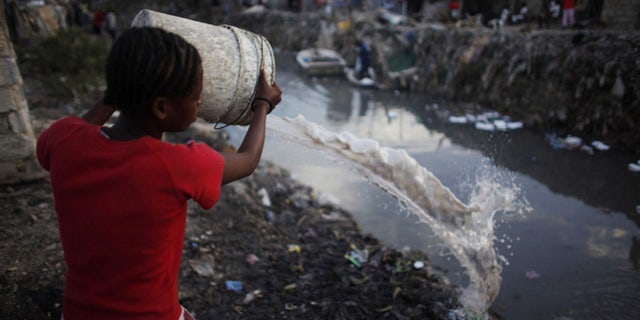 Resident throws dirty water into a drain which leads into the sea in Port-au-Prince in file photo.