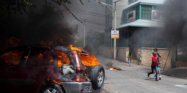 People run past the Best Western hotel during a protest over the cost of fuel in Port-au-Prince, Haiti, Saturday, July 7, 2018.