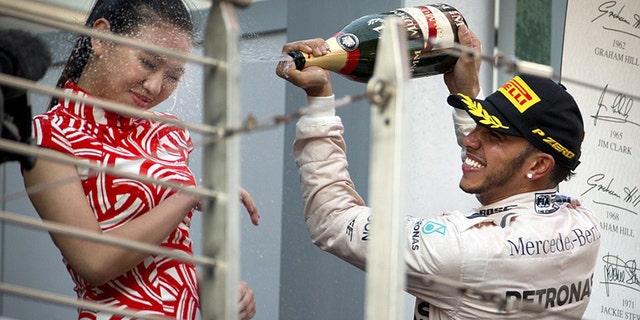 Lewis Hamilton sprays champagne on a "grid girl" after winning the 2015 Chinese Grand Prix.