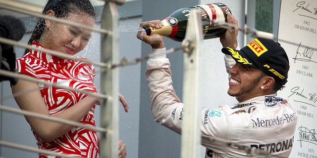 Lewis Hamilton sprays champagne on a "grid girl" after winning the 2015 Chinese Grand Prix.