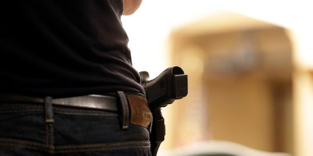 A Glock handgun is holstered on the side of Kristopher Kranz of Bloomington, Minn., as he listens during public testimony Tuesday, Aug. 20, 2013 in St. Paul, Minn. in front of a panel studying whether Minnesota's rules for carrying a gun in the Capitol need revising, (AP Photo/Jim Mone)