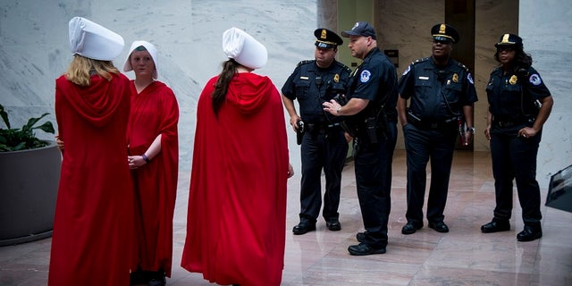 Pro-choice activists dressed like characters in 'The Handmaid's Tale' protested Supreme Court Justice Brett Kavanaugh's confirmation, saying he would be a decisive vote against Roe v. Wade.