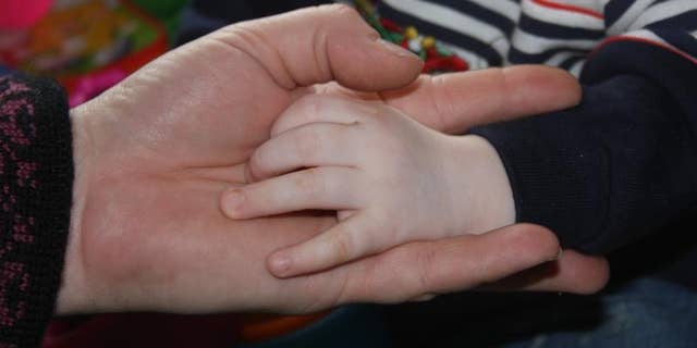 Ann Bates, of Bernville, Pa., holds the hands of the 18-month-old Russian boy she hopes to adopt.