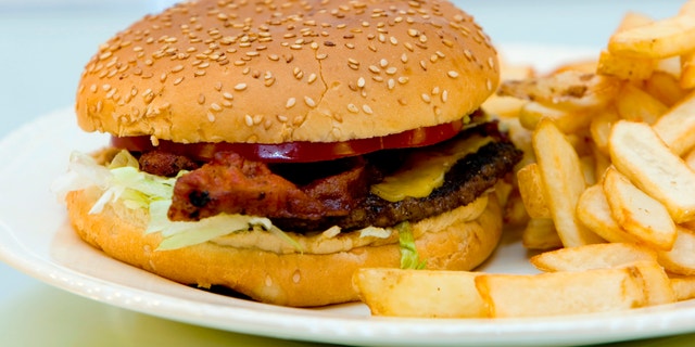 Bacon cheeseburger with french fries on a plate.