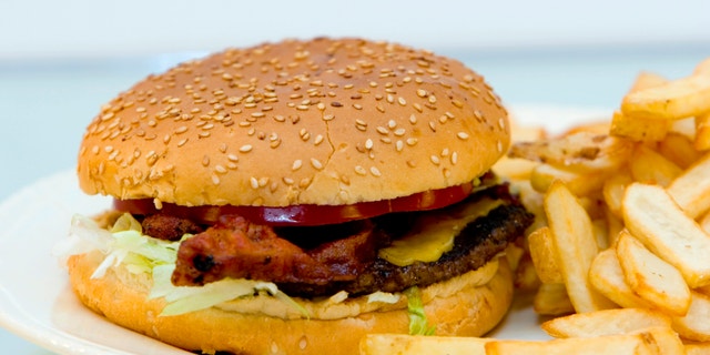 Bacon cheeseburger with french fries on a plate.