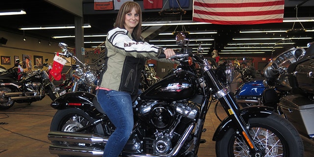 In this Dec. 12, 2017, photo, Terri Meehan poses on a 2018 Harley Softail Slim in Milwaukee's House of Harley. Meehan took a riding course at the dealership as part of Harley-Davidson's "Riding Academy," an initiative the company hopes will help bring new customers. (AP Photo/Ivan Moreno)