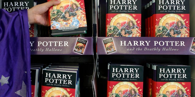 An employee dressed up as a character from the Harry Potter series grabs a copy of the seventh and final Harry Potter book.