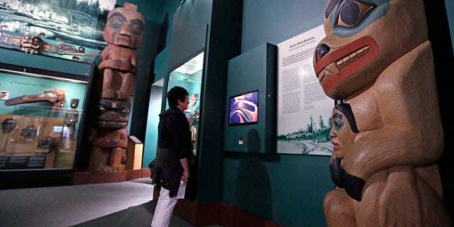 A visitor stands among totem poles as she watches a video as part of Hall of the North American Indian exhibit, at the Peabody Museum of Archaeology & Ethnology at Harvard University in Cambridge, Mass., Thursday, Oct. 13, 2016.