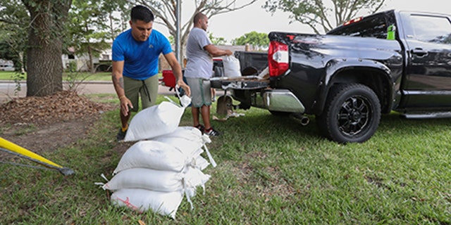 Albert Martinez and Victor Valerio fill bags with dirt from a pickup, Aug. 24, 2017
