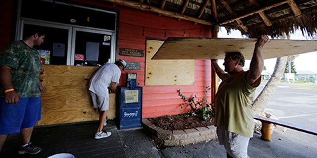 Mac Owens, left, Mark Jones, center, and Kelly Owens, right, board up their business in preparation for Hurricane Harvey, Aug. 24, 2017