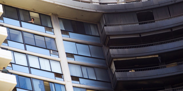 With the damage of the fire nearby, a woman attempts to clean her window sill at the Marco Polo residence, Saturday, July 15, 2017, in Honolulu.