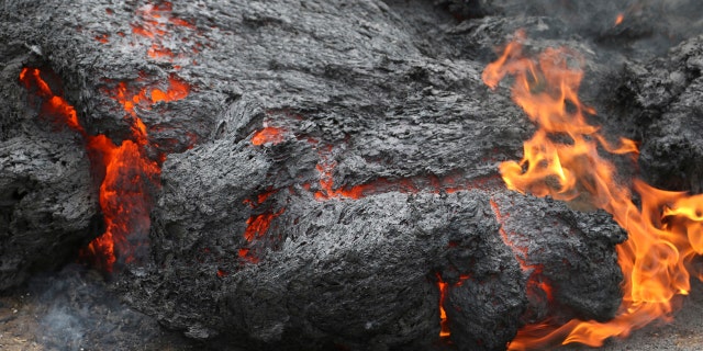 In this May 5, 2018, file photo, lava burns across a road in the Leilani Estates subdivision near Pahoa, Hawaii.
