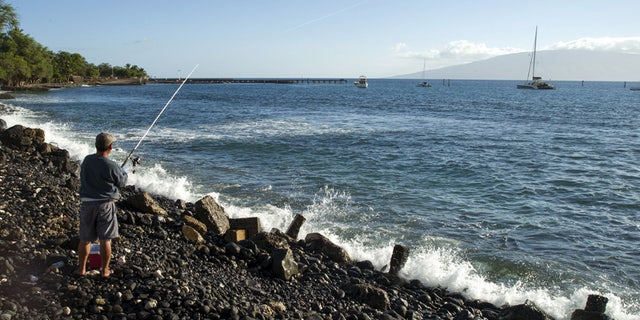 A fisherman casts his reel in waters off the coast of Maui, Hawaii.