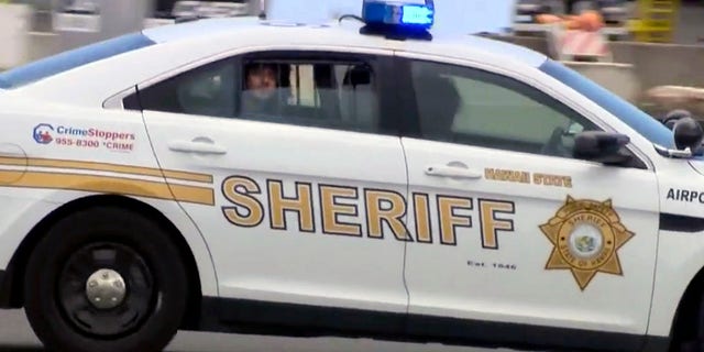 Suspect Anil Uskanli is driven away from the airport in the back of a sheriff's car in Honolulu after being pulled from an American Airlines flight, May 19, 2017.