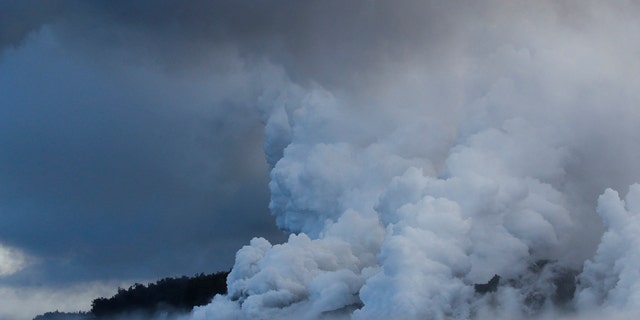 Plumes of steam rise as lava enters the ocean near Pahoa, Hawaii.