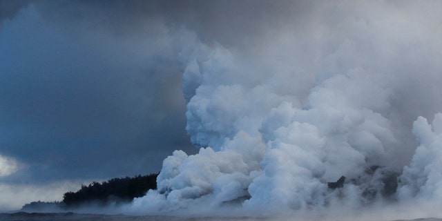 Plumes of steam rise as lava enters the ocean near Pahoa, Hawaii.