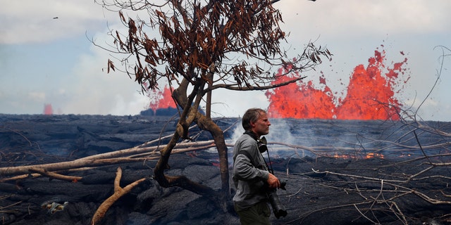 Photographer Carsten Peter, of Germany, watches lava erupt from fissures in the Leilani Estates subdivision near Pahoa, Hawaii, Tuesday, May 22, 2018.