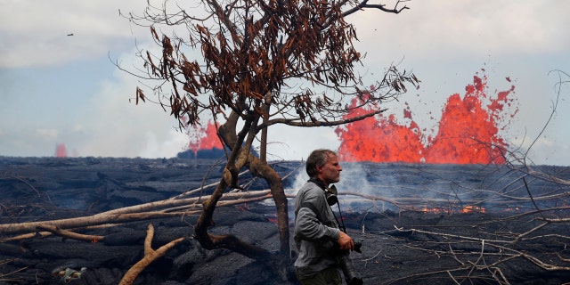 Photographer Carsten Peter, of Germany, watches lava erupt from fissures in the Leilani Estates subdivision near Pahoa, Hawaii, Tuesday, May 22, 2018.
