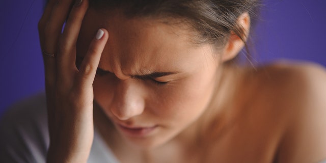 Teen woman with headache holding her hand to the head