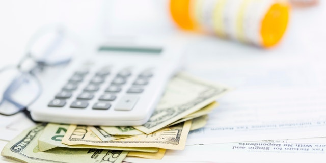 Calculating income tax return with folded cash on a table.