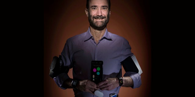 In this photo provided by Steve Fisch, Michael Snyder, professor and chair of genetics at the Stanford University School of Medicine sports wearable gadgets. Wearable gadgets gave a Snyder an early warning that he was getting sick before he ever felt any symptoms of Lyme disease. (Steve Fisch via AP)