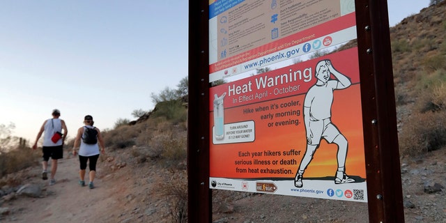 A sign warns hikers about severe heat as they begin their hike at sunrise to avoid the excessive heat, Friday, June 16, 2017, in Phoenix.