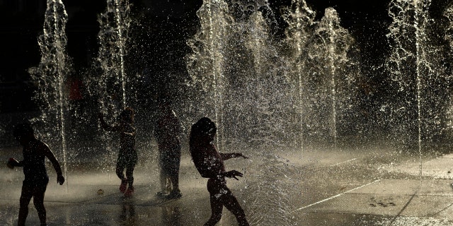 FILE - In this June 8, 2016, file photo, children cool off under water fountains on a sunny day, in Pamplona northern Spain. (AP Photo/Alvaro Barrientos, File)