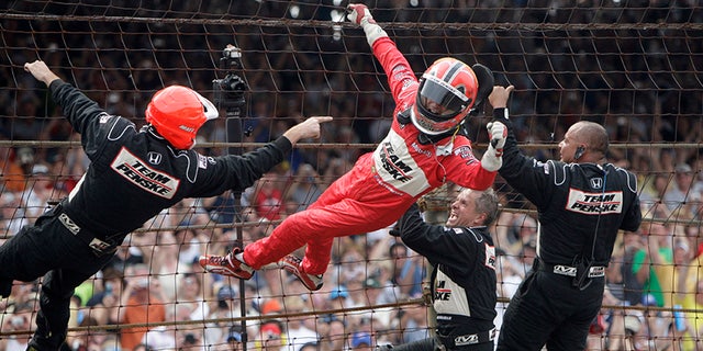 Castroneves climbs the catch fence at the Indianapolis Motor Speedway after his third Indy 500 win