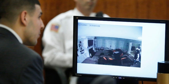 March 12, 2015: Former New England Patriots football player Aaron Hernandez, left, watches as a still frame from surveilance video is displayed on a monitor during his murder trial.