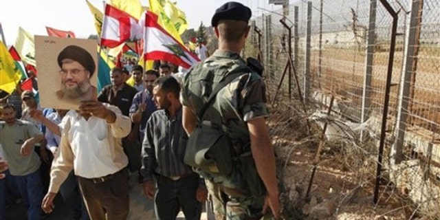 June 2: A Hezbollah supporter holds up a poster of Hezbollah leader Sheik Hassan Nasrallah as he protests with others along the Lebanese-Israeli border in southern Lebanon.