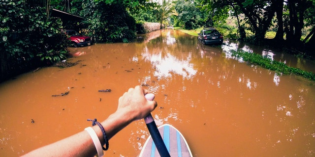 This Sunday, April 15, 2018, photo provided by Kauai resident James Hennessy shows the view as he maneuvers a stand-up paddleboarding along his flooded street in Haena, Hawaii.
