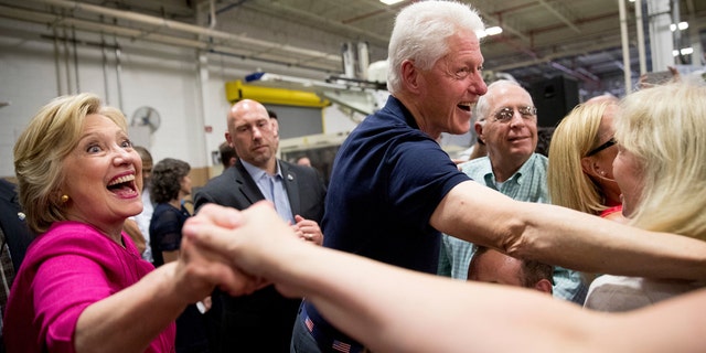Hillary Clinton and Bill Clinton shake hands with supporters.