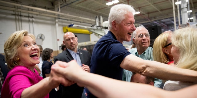 Hillary Clinton, far left, and Bill Clinton, right, shake hands with supporters.
