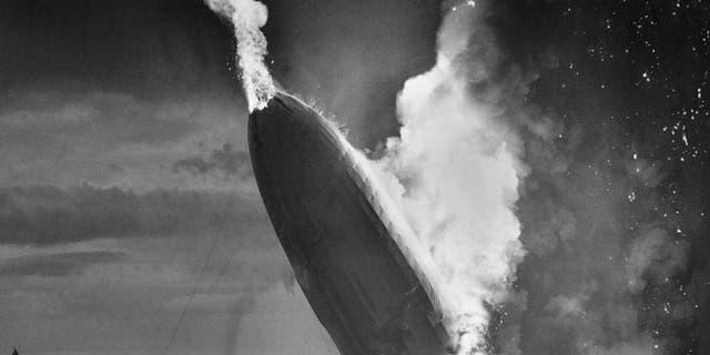 FILE - In this May 6, 1937 file photo, the German dirigible Hindenburg crashes to earth in flames after exploding at the U.S. Naval Station in Lakehurst, N.J. Only one person is left of the 62 passengers and crew who survived when the Hindenburg burst into flames 80 years ago Saturday, May 6, 2017. Werner Doehner was 8 years old when he boarded the zeppelin with his parents and older siblings after their vacation to Germany in 1937. The 88-year-old now living in Parachute, Colo., tells The Associated Press that the airship pitched as it tried to land in New Jersey and that "suddenly the air was on fire." (AP Photo/Murray Becker, File)