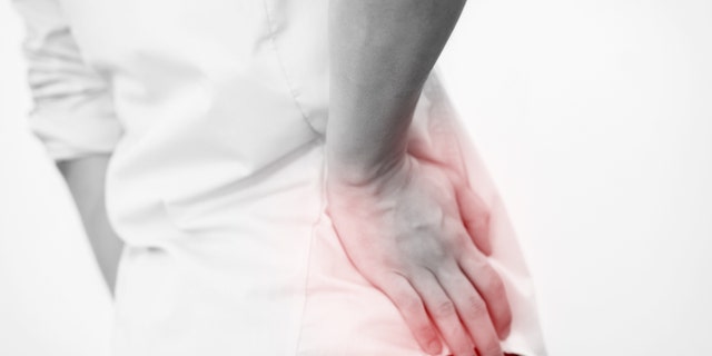 Young man in casual office shirt having hip pain (Focus on hips)