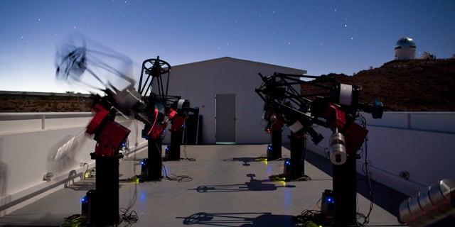 The MEarth-South telescope array, located on Cerro Tololo in Chile, searches for planets by monitoring the brightness of nearby, small stars. This long-exposure photograph shows MEarth-South telescopes observing at night; the blurred telescope is slewing from one star to another.