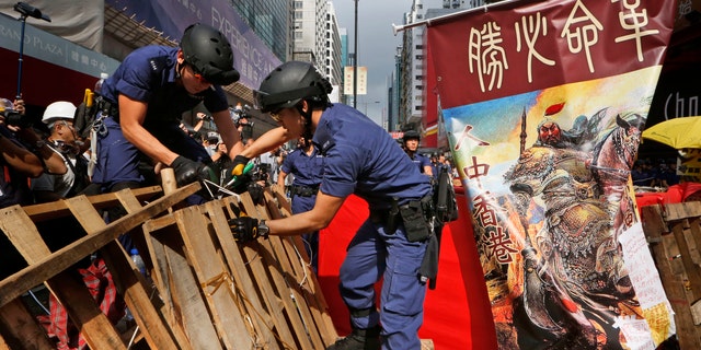 Nov. 26, 2014: Police officers remove the barricades made up mostly of wooden pallets by demonstrators decorated with a banner